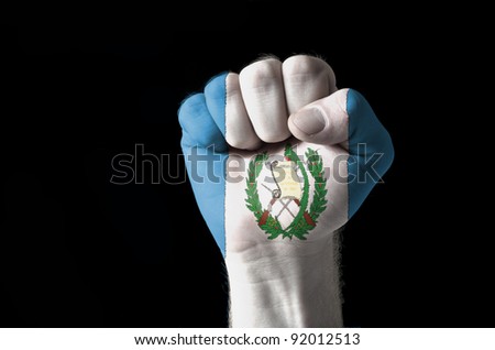 Low key picture of a fist painted in colors of guatemala flag
