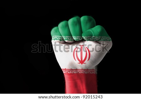 Low key picture of a fist painted in colors of iran flag