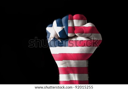 Low key picture of a fist painted in colors of liberia flag