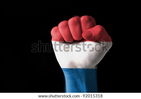 Low key picture of a fist painted in colors of netherlands flag