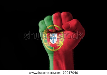 Low key picture of a fist painted in colors of portugal flag