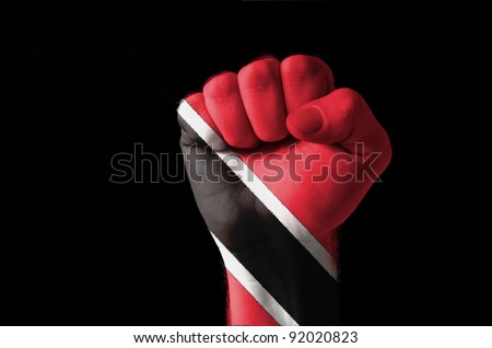 Low key picture of a fist painted in colors of trinidad tobago flag