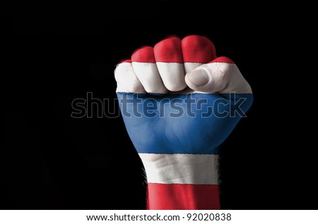 Low key picture of a fist painted in colors of thailand flag