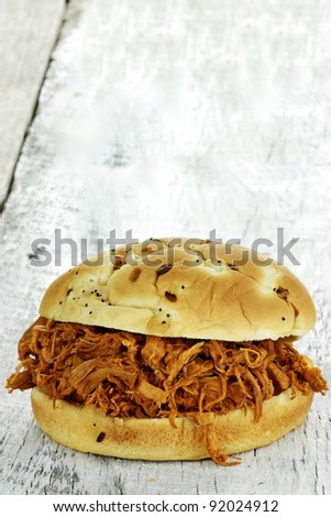 Close up of pulled chicken sandwich on a rustic background.