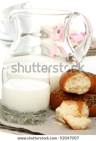 Bagel with poppy seeds a pitcher of milk on a white background.