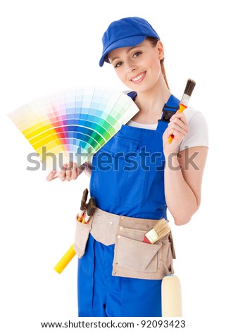 Young woman in  coverall with a color guide and paintbrushes on a white background.