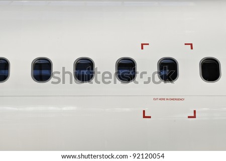 Windows of airplane with emergency sign.