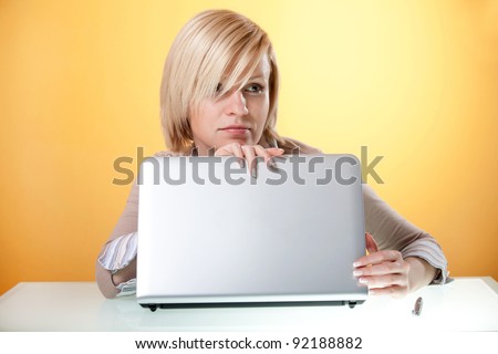 Thoughtful young woman sitting at the table with an open laptop