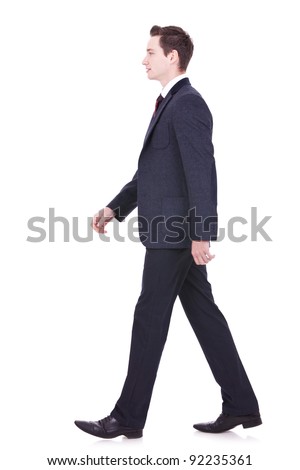 picture of a young business man walking forward - side view