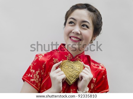 Beautiful asian woman wear cheongsam and holding golden heart