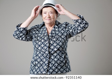 Happy beautiful older lady posing on gray background.
