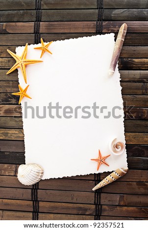 Marine themed frame of paper sheet and some seashells on a wooden mat.