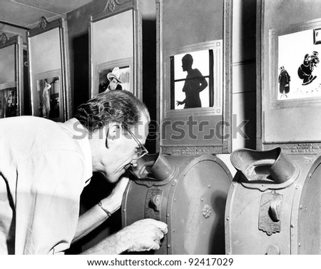 Man looking into a nickelodeon film machine