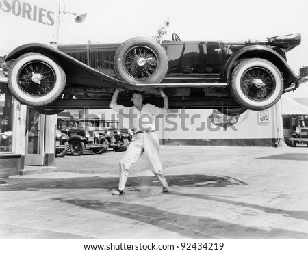 Strong man lifting a car over his head Royalty-Free Stock Photo #92434219