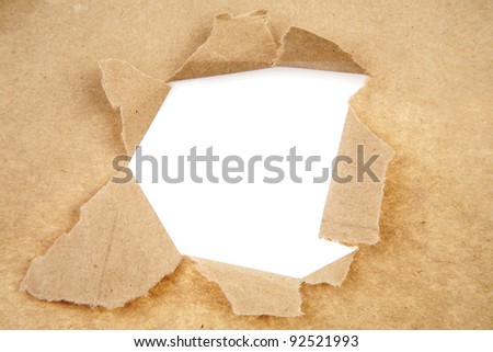 Hole ripped in brown paper on white background