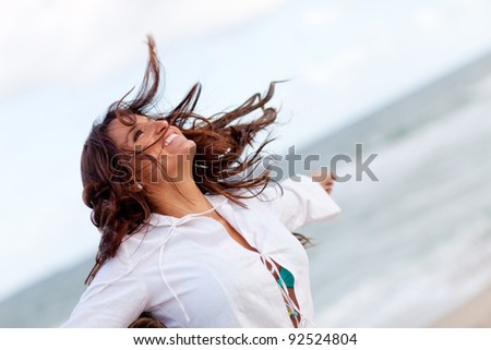 Woman enjoying the windy weather at the beach and relaxing