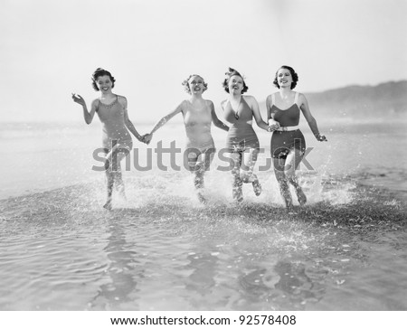 Four women running in water on the beach Royalty-Free Stock Photo #92578408