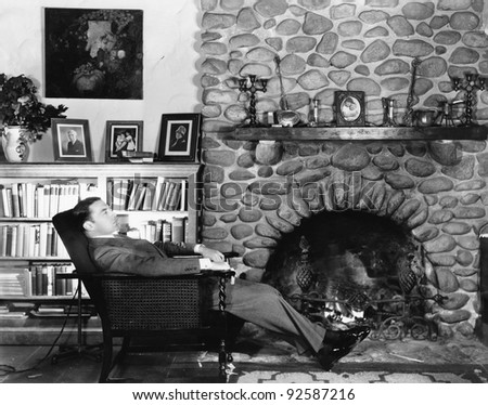 Profile of a young man resting in an arm chair near a fireplace