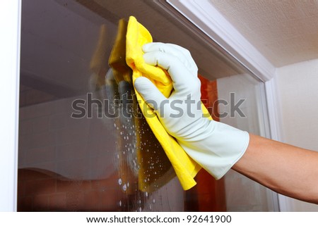 Gloved hand cleaning window. Royalty-Free Stock Photo #92641900