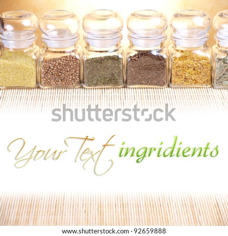 Kitchen glass jars with ingridients dried spices, herbs like savory, coriander and other with white copy space for your text