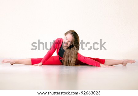 Pretty flexible dancer woman sit on floor in dance studio and stretching