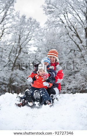 Mother whit children Sitting On A Sled In The Snow