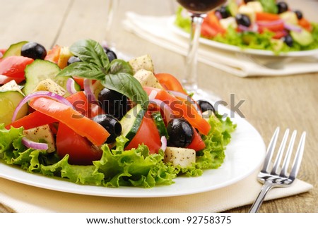 Greek salad and glass of red wine on the oak table