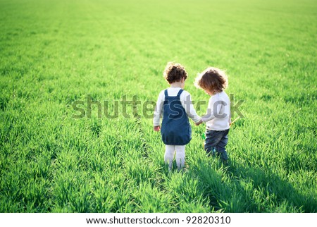 Two children going in spring green field Royalty-Free Stock Photo #92820310
