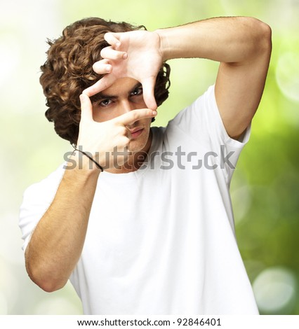 portrait of young man gesturing frame against a nature background