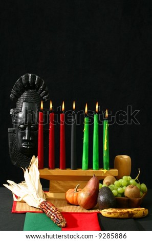 Kwanzaa display with large corn, fruits, and vegetables with Kwanzaa flag