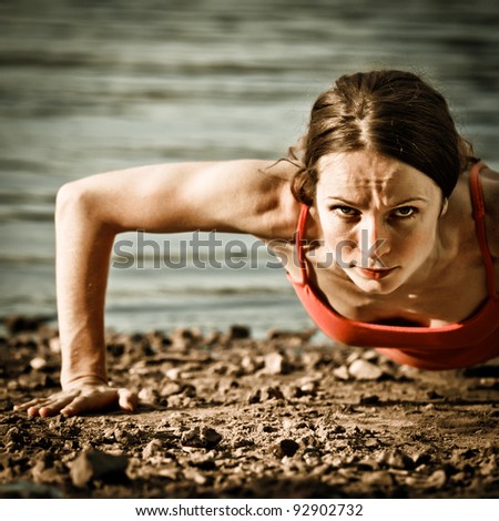 Strong woman doing push up at the beach