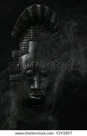 African Tribal Mask surrounded by smoke on black background