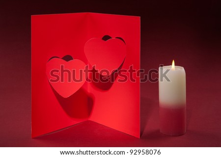 candle and a card for Valentine's Day with two hearts on a red background