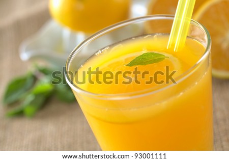 Freshly squeezed orange juice with drinking straws and orange slice, mint leaf on top of the juice (Selective Focus, Focus on the mint leaf in the glass) Royalty-Free Stock Photo #93001111
