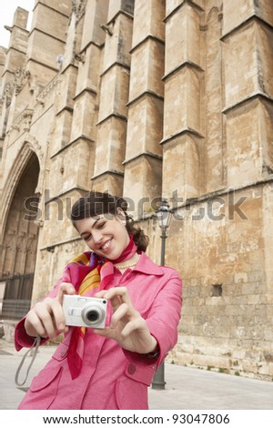 Stylish young tourist taking pictures near a monument.