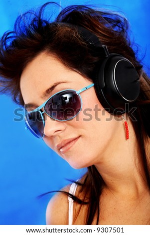 beautiful woman listening and wearing sunglasses over a blue background