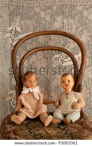dolls boy and girl sitting on an old chair with floral background square