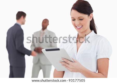 Saleswoman with tablet and colleagues behind her against a white background