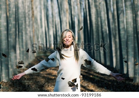 Beautiful blonde girl with falling leaves in the autumn park
