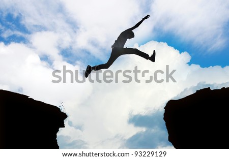 Silhouette of young man jumping over a cliff Royalty-Free Stock Photo #93229129