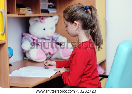 happy young school girl doing homework at home