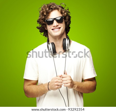 portrait of a young man smiling with headphones over a green background