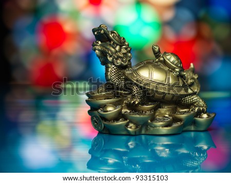 golden feng-shui prosperity dragon statuette, against a colorful star-shaped lights background
