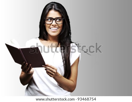 portrait of young student holding a opened book and smiling over grey background