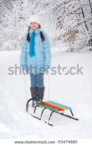 girl with a sledge in snowy forest