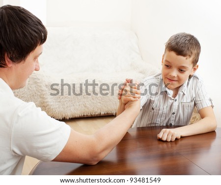 Father and son arm wrestling. Dad play with child