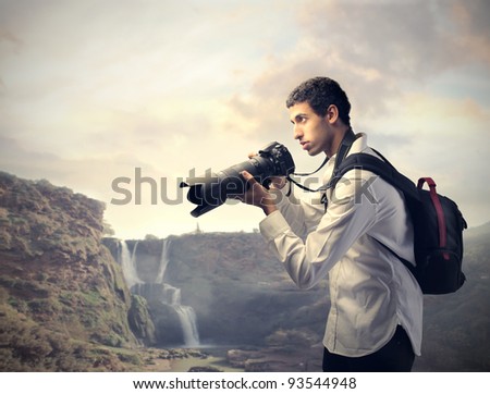 Young photographer holding a camera with landscape in the background