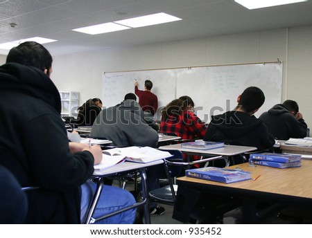 A photo of students listening to the teacher in a classroom
