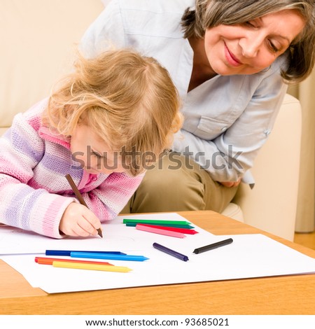 Grandmother and little girl drawing together with pencils at home