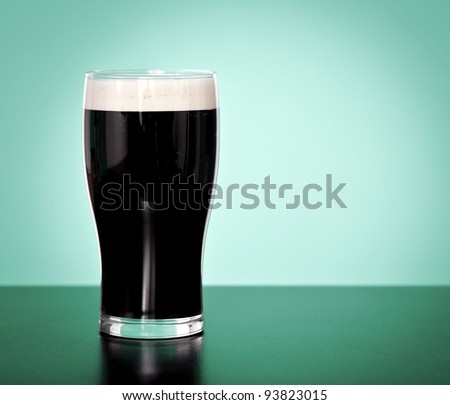 Pint of Irish stout beer on a green background